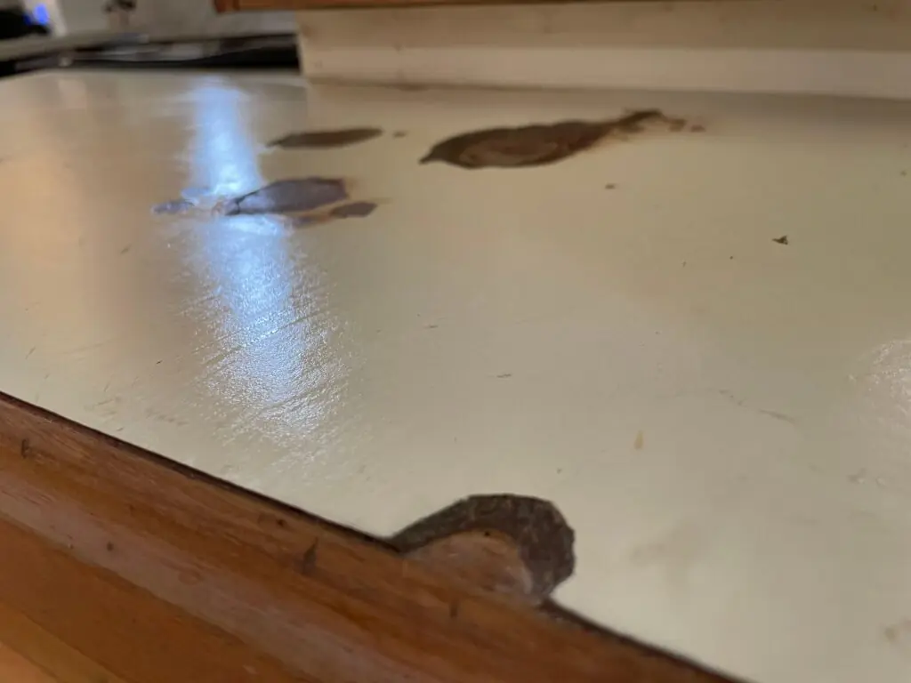 Kitchen countertop with chipped edges, deep scratches, and surface damage requiring replacement.