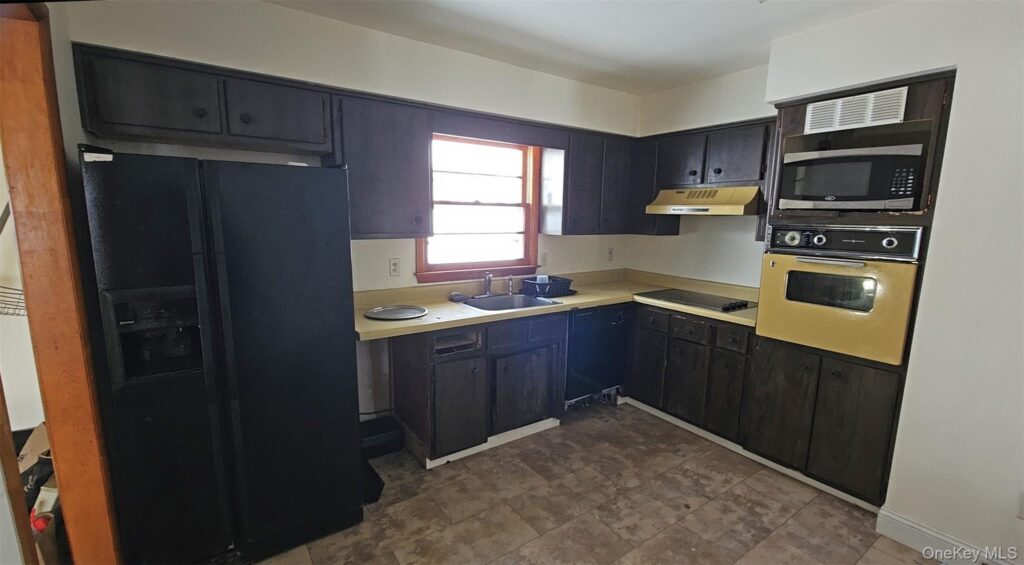 Kitchen with dark wood cabinets and laminate countertops that no longer match modern design preferences.