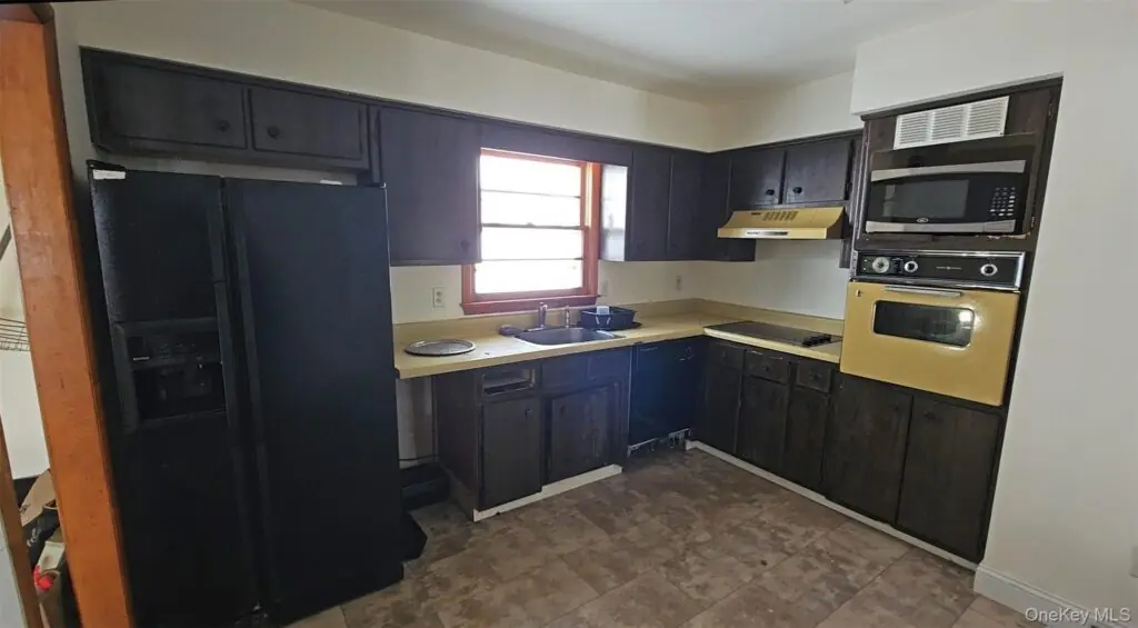Kitchen with dark wood cabinets and laminate countertops that no longer match modern design preferences.