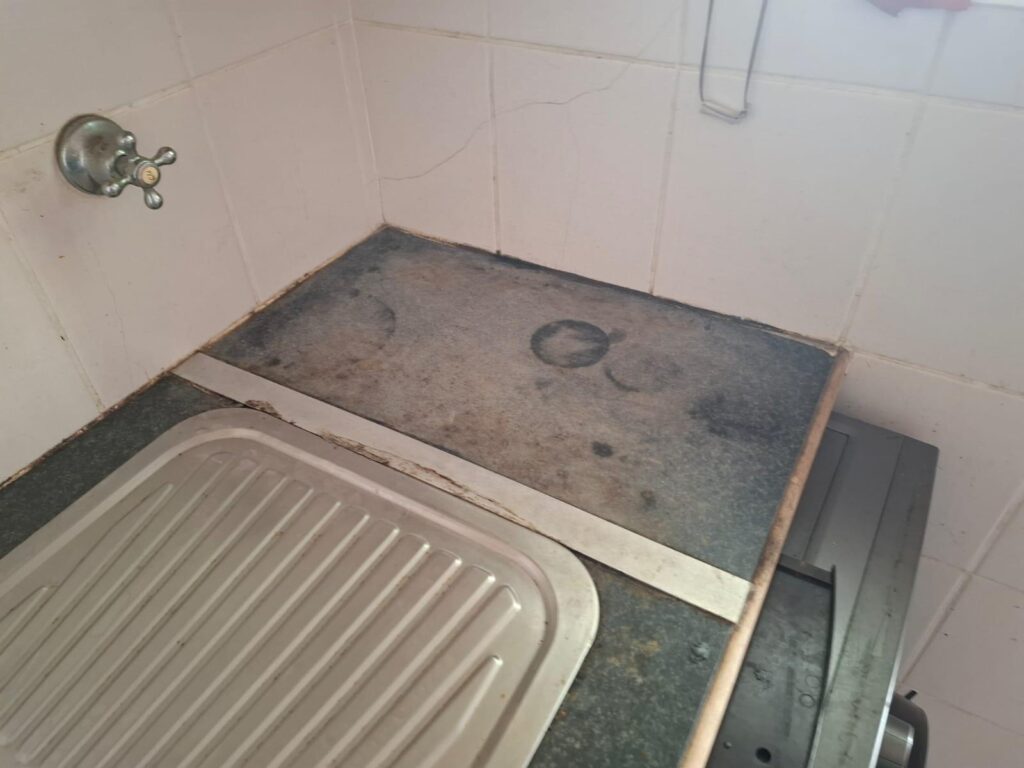 Old laminate kitchen countertops with cracks, stains, and visible signs of wear before renovation.