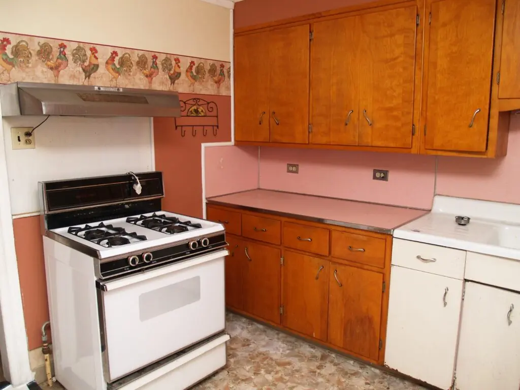 Outdated kitchen with old cabinets, dated finishes, and an uninspiring design before remodeling.