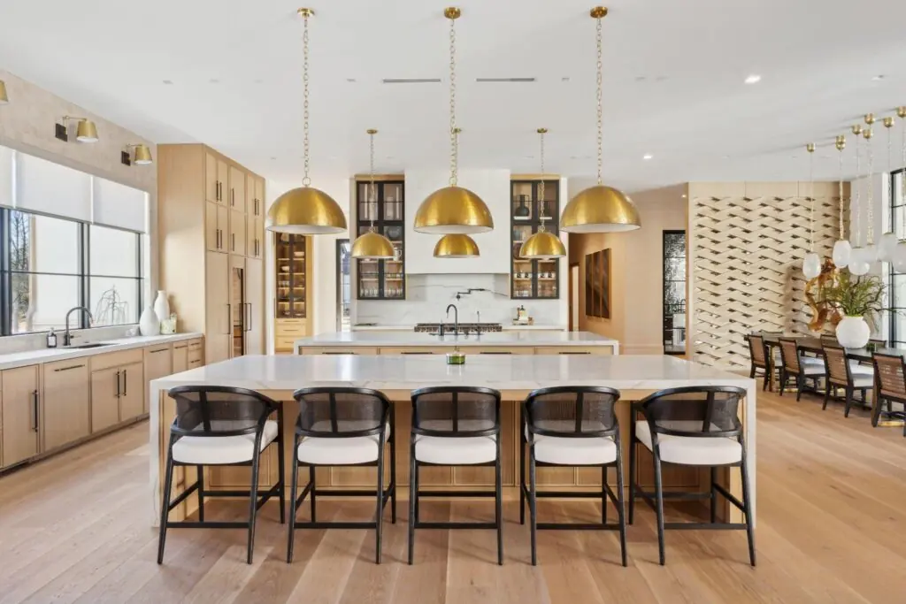 Modern kitchen with oversized pendant lights above a quartz island and layered LED lighting.