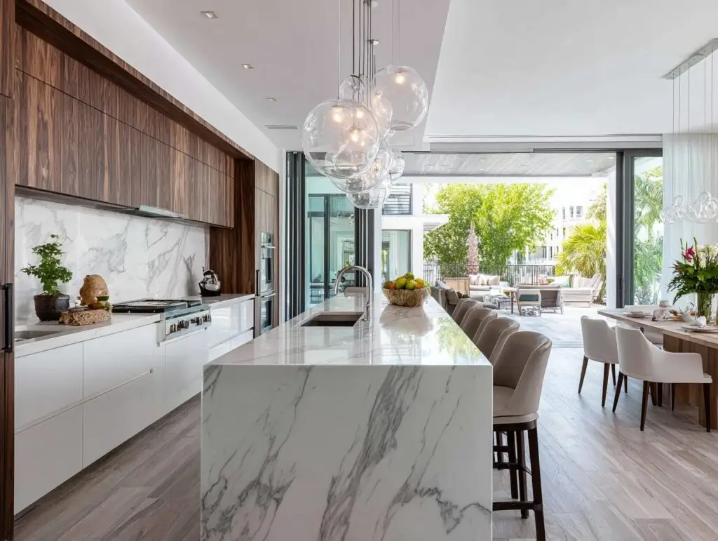 Modern kitchen with a quartzite waterfall island, elegant pendant lighting, and spacious seating area.