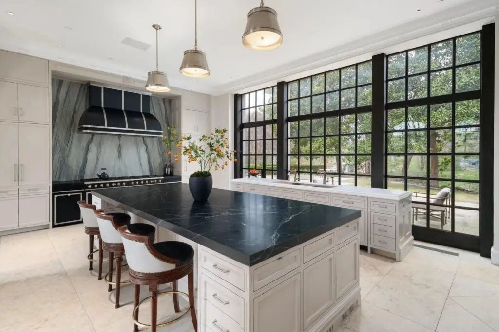 Open-concept luxury kitchen with natural wood cabinetry, large windows, elegant stone finishes, and contemporary design.